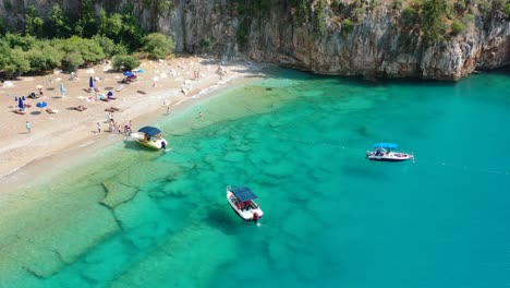 Aerial-drone-circling-small-tourist-boats-anchored-in-the-transparent-and-crystal-clear-turquoise-blue-water-of-the-Mediterranean-Sea