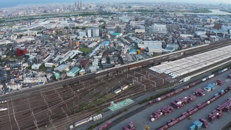 Luftaufnahme,-Als-Der-Shinkansen-Hochgeschwindigkeitszug-Den-Bahnhof-Und-Das-Frachtschifffahrtsdepot-Passiert