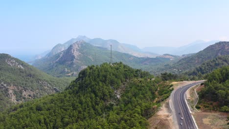 Aerial-scenic-view-over-the-peaks-of-the-rough-Taurus-Mountain-landscape-and-highway-passing-through-the-valley-near-the-Mediterranean-coast-of-Antalya-Turkey-on-a-sunny-summer-day