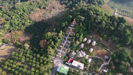 Luftdrohne-Eines-Einzigartigen-Tempels-Mit-Einem-Goldenen-Buddha-Auf-Einem-Berg,-Umgeben-Von-Kokospalmen-In-Ao-Nang-Krabi,-Thailand