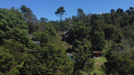 Drone-shot-of-an-eco-farm-in-Hogsback,-South-Africa---drone-is-reversing-from-a-self-made-guest-room