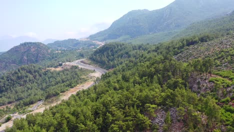 Drone-Aéreo-Que-Revela-Una-Carretera-De-Montaña-En-Las-Colinas-De-Antalya,-Turquía,-Rodeada-Por-Un-Denso-Bosque-En-Un-Día-Soleado-De-Verano