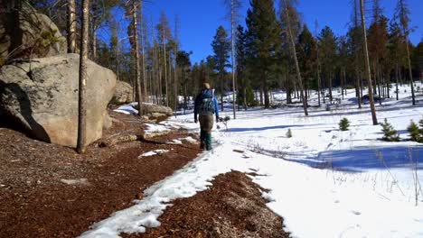 Solo-Männchen,-Das-Von-Der-Kamera-Weg-Auf-Einem-Verschneiten-Und-Felsigen-Pfad-In-Colorado-Wandert