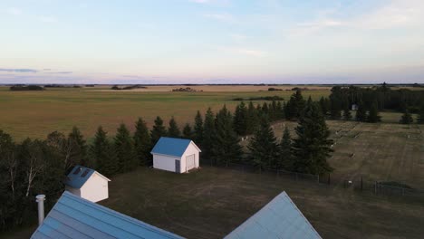 Beautiful-white-and-blue-country-church-next-to-a-small-cemetery-and-two-huts-at-sunset-in-Alberta,-Canada