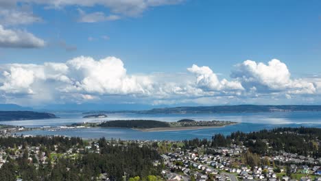Aerial-shot-of-Whidbey-Island's-Oak-Harbor-surrounded-by-clouds-on-a-warm-summer's-day