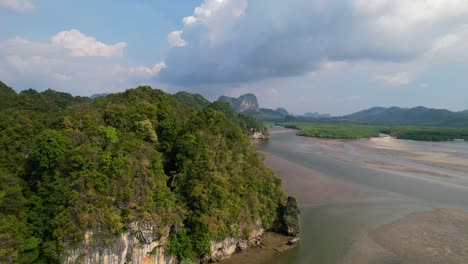 drone-passing-a-limestone-mountain-revealing-the-river,-mangroves,-and-sandbar-during-low-tide-on-a-sunny-day-in-Ao-Thalane-Krabi-Thailand