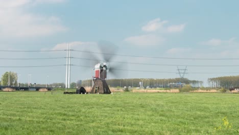 Time-Lapse-Of-A-Working-Windmill-Structure-Stationed-In-The-Grassland,-Near-A-Public-Highway-During-The-Day