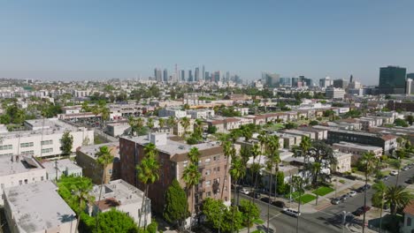 Drone-Shot-of-Los-Angeles-Residential-Neighborhood-on-Sunny-Day,-Downtown-LA-Skyline-in-the-Distance-on-Horizon