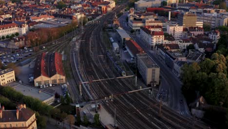 Europe-train-entering-city-on-tracks-drone-follow-shot-at-golden-hour-4k-30p