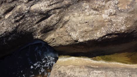 A-shallow-creek-erodes-stone-as-it-trickles-down-Giant's-Cauldron-in-Algorfa-Alicante,-Spain---ascending-aerial-view