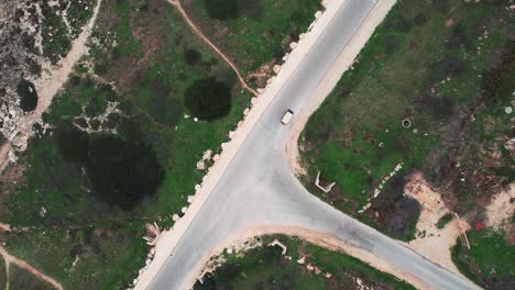 Aerial-drone-shot-of-a-golf-car-driving-on-a-road