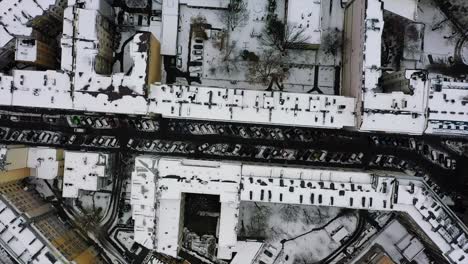 Aerial-view-over-snowy-buildings-and-streets-in-Warsaw,-Poland---overhead,-drone-shot