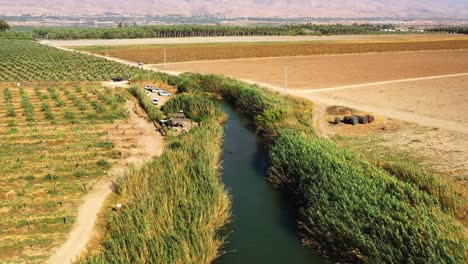 Long-narrow-natural-pool-at-Hakibbutzim-River-in-Beit-She'an-between-Jezreel-Valley-and-Jorden-river-on-a-windy-day-as-a-car-drives-slowly-along-the-dirt-road