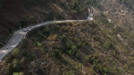 Un-Dron-Sigue-A-Un-Automóvil-Que-Conduce-Por-Una-Carretera-Estrecha-Del-Himalaya-En-La-India-Región-Montañosa-De-Himachal-Pradesh-Destino-De-Viaje-De-Trekking