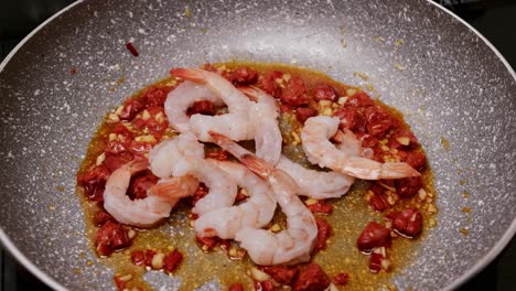 Placing-peeled-shrimp-in-a-frying-pan-where-chorizo-sausage-and-garlic-are-fried-with-oil