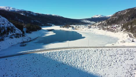 Aerial-rotating-in-front-of-Tunhovd-dam---Statkraft-operated-water-reservoir-for-hydroelectric-powerplant-Nore---Winter-seeing-both-dam-landfill-and-water-inside---Norway
