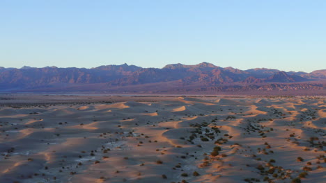 Wavy-sand-dunes-with-mountains-in-the-background