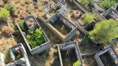 aerial-top-down-view-circling-the-abandoned-ruins-of-whats-left-of-homes-in-the-village-of-Kayakoy-in-Fethiye-Turkey-where-there-are-no-roofs-and-only-overgrown-trees