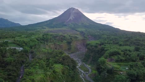 Vista-Aérea-De-Mostrar-La-Pendiente-Del-Volcán-Merapi-En-Indonesia-Y-El-Camino-De-Lava-Seca-Durante-Las-Nubes-En-El-Cielo---Bego-Pendem,-Indonesia
