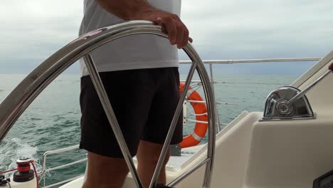 Midsection-of-a-captain-steering-a-sailing-boat-on-an-overcast-day