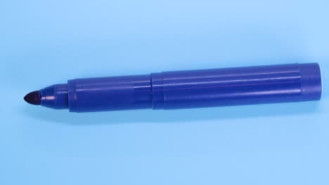 Blue-marker-pen-rotating-on-blue-surface-background,-macro-shot-close-up-view-detail
