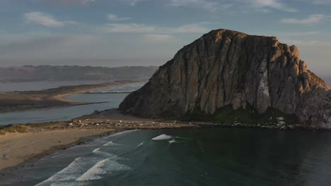 Luftaufnahme-Von-Morro-Bay-Rock-In-Kalifornien-USA-Während-Des-Sonnenuntergangs-Mit-Sandigen-Inseln-Und-Bergen-In-Der-Ferne