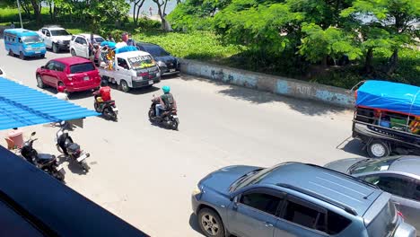 Rush-hour-traffic-at-lunchtime-in-the-city-centre-of-capital-city-Dili,-Timor-Leste,-motorbikes,-cars,-buses,-and-public-transport-microlets-on-main-road