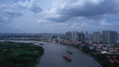 Aerial-panning-shot-of-Large-river-boats-carrying-shipping-containers-on-the-Saigon-River-in-Ho-Chi-Minh-City