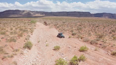 Aerial-shot-pulling-away-from-a-vehicle-driving-through-Utah's-rough-desert-terrain