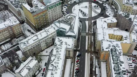Aerial-view-overlooking-trams-on-snowy-streets-of-Warsaw,-winter-in-Poland---rising,-high-angle,-drone-shot