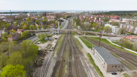 Aerial-view,-pedestrian-bridge-that-goes-over-busy-car-street-and-train-tracks