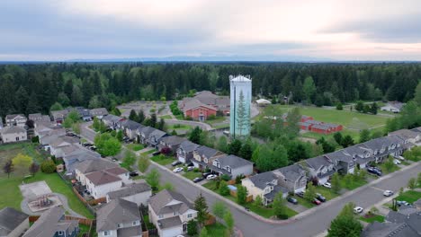 Orbiting-aerial-shot-around-a-suburban-water-tower-with-a-neighborhood-in-the-foreground
