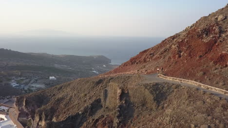 Luftspuren-Zwei-Wanderer,-Die-Auf-Santorini,-Griechenland,-Auf-Einem-Bergpfad-Spazieren