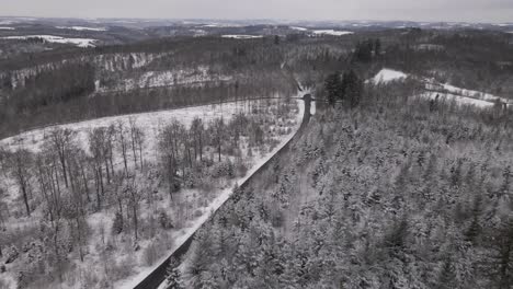 Open-highway-running-through-white,-snow-covered-forest-and-valleys-in-the-picturesque-countryside-of-West-Germany-near-Rhineland-Palatinate-and-North-Rhine-Westphalia