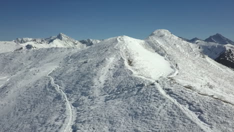 Lone-hiker-jogs-up-snowy-trail-toward-blue-sky-Tatra-mountain-summit