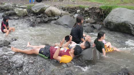 Yogyakarta,-Indonesia---May-26,-2022-:-Asian-kids-having-fun-playing-in-the-river-with-splashing-water-together
