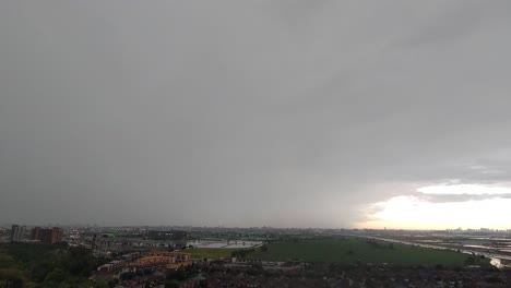 Rainy-day-timelapse,-cloudy-sky,-lightining-over-the-city-view-and-green-meadow