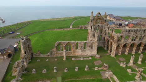 Whitby-Abbey-ruins-surrounded-by-green-meadows-with-sea-in-background,-Yorkshire-in-UK