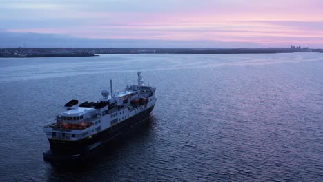 Travel-cruise-ship-anchored-near-coast-of-Iceland-enjoying-colorful-sunset