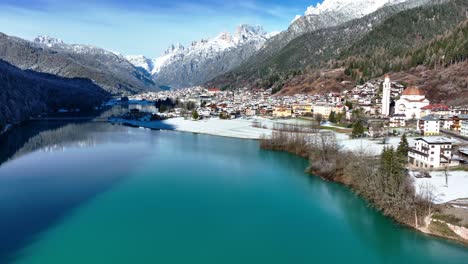 Drone-Aerial-view-of-mountains,-lake-and-small-town-with-snow-in-winter-in-Europe