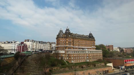 Panoramic-video-of-the-Grand-Hotel,-a-Grade-2-listed-building,-reflected-in-the-wet-sand-of-Scarborough-beach-on-a-fine-winter-day