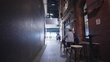 Moving-past-an-alley-way-bar-while-customers-sit-and-drink-outside