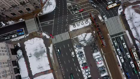 Aerial-view-overlooking-trolleys-on-the-snowy-streets-of-Warsaw,-Poland---rotating,-high-angle,-drone-shot