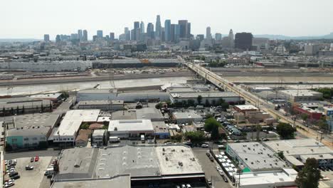 Erhebt-Sich-über-Dem-Industriegebiet-Und-Den-Lagerhäusern-Von-Los-Angeles,-Um-Die-Berühmte-Skyline-Zu-Enthüllen---Aufsteigende-Luftaufnahme