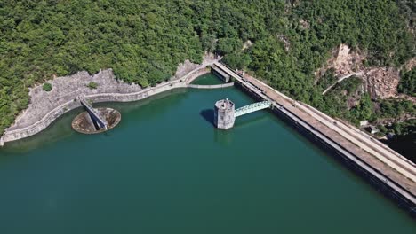 Eine-Dynamische-Luftaufnahme,-Die-Den-Staudamm-Und-Den-Kontrollturm-Des-Shing-mun-reservoirs-In-Hong-Kong-Umkreist