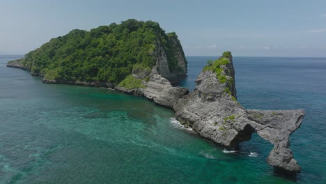 Wild-tropical-remote-island-with-steep-rock-cliffs,-Nusa-Batupadasan,-aerial