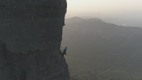 Filmische-Drohnenaufnahme-Von-Kletterern,-Die-Eine-Sportroute-Mit-Mehreren-Seillängen-Auf-Einem-Basaltfelsengipfel-In-Den-Bergen-Der-Sahyadri-Kette-In-Indien-Erklimmen