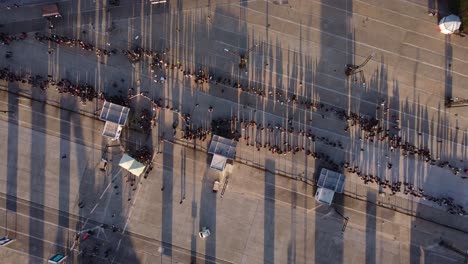 Aerial-drone-top-down-pov-over-long-queue-of-people-waiting-in-Buenos-Aires-at-sunset