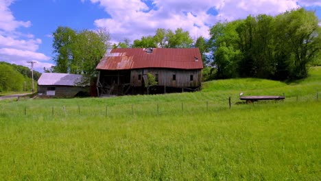 low-aerial-of-old-rusted-barn-and-farm-equipment-near-mountain-city-tennessee