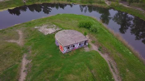 Aerial-point-of-interest-birdseye-view-of-abandoned-concrete-seaside-fortification-building,-Southern-Forts-near-the-beach-of-Baltic-sea-in-Liepaja-at-overcast-summer-day,-wide-drone-shot-rotate-right
